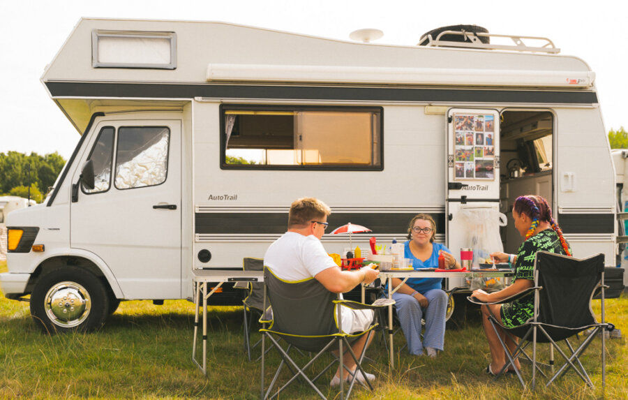 Three people sitting outside their caravan at Electric Picnic